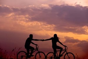 Dos personas disfrutando un paseo romántico en bicicleta durante el atardecer